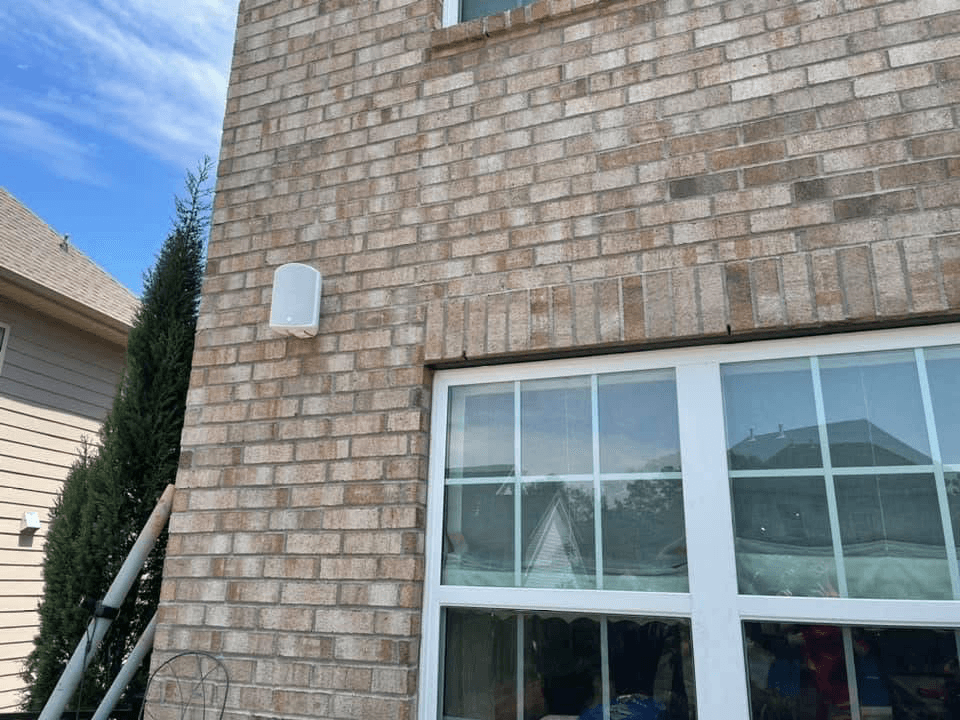 Wall-mounted outdoor speaker on brick exterior above windows