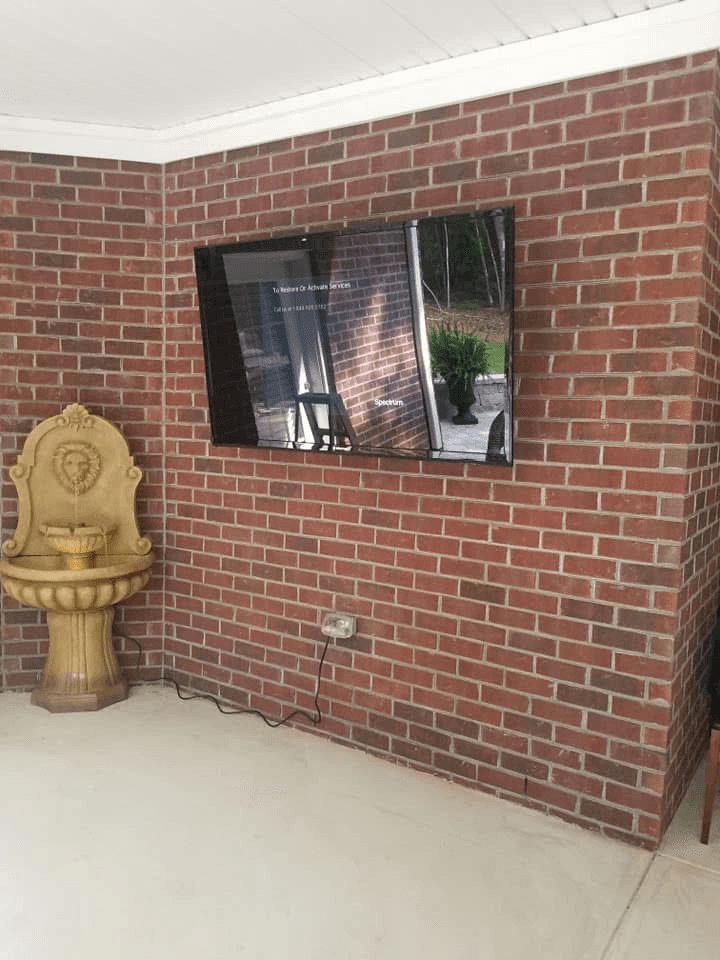 TV mounted on brick wall in covered patio with fountain
