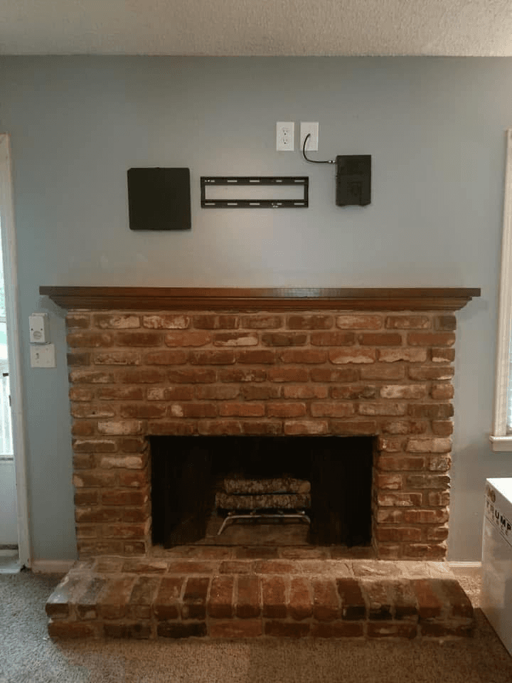 TV mount hardware and receiver shelf on brick fireplace wall