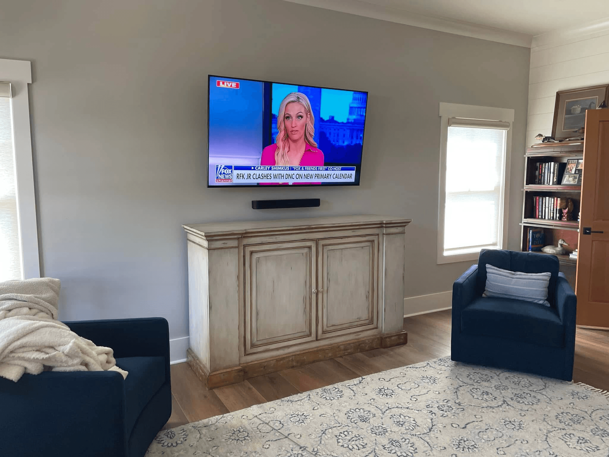 TV wall-mounted with Sonos soundbar above distressed wood cabinet in living room